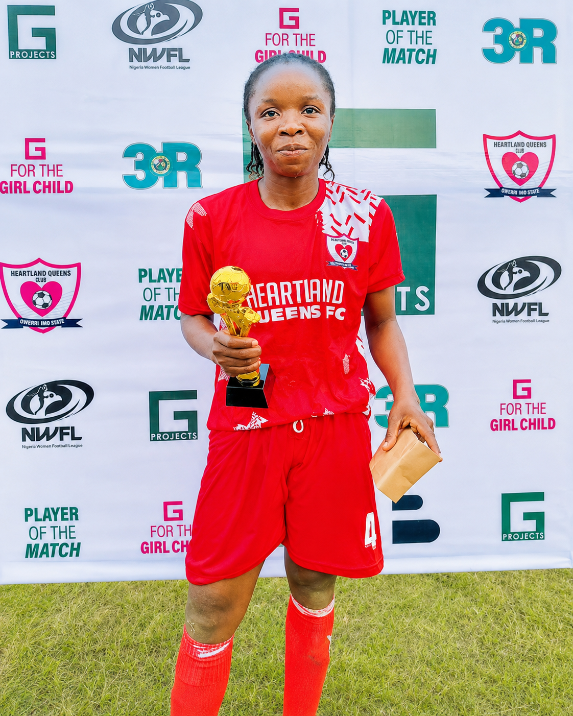 Red jersey footballer holding player of the match trophy